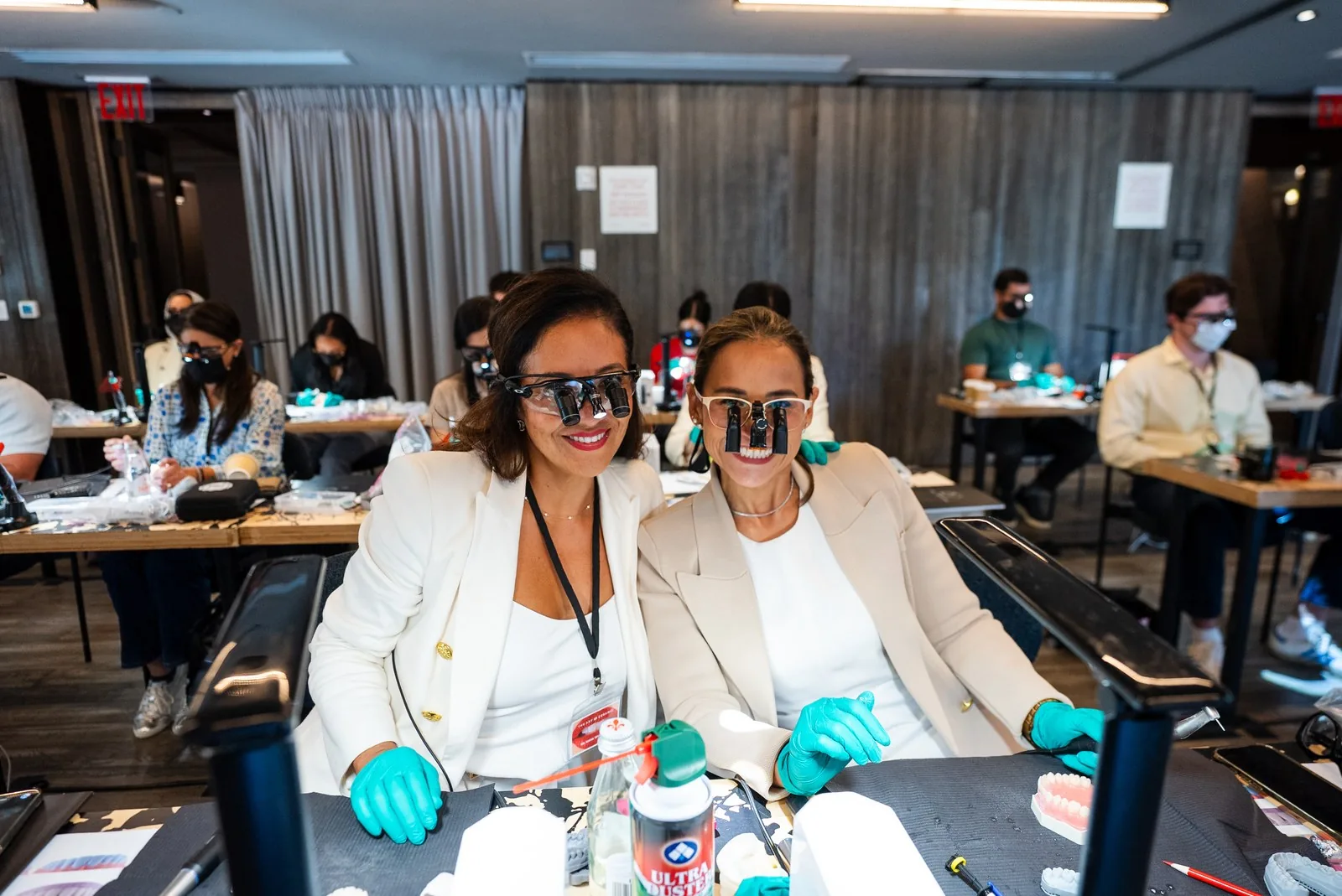 Two dentists in white blazers, gloves and loupes smile at their Art of Ceramic workstation