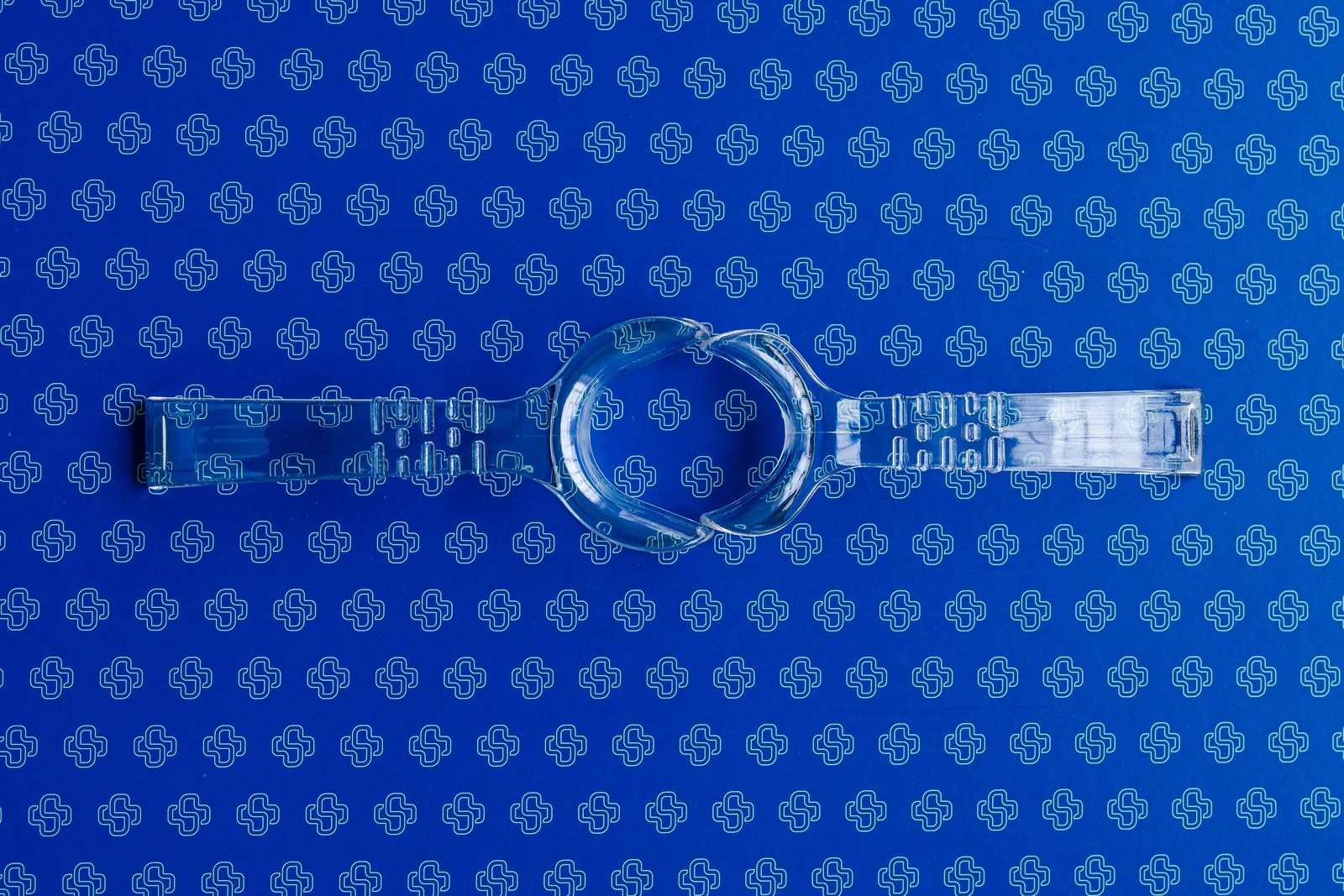 A clear double-ended lip retractor for dental photography on a blue Stribe backdrop