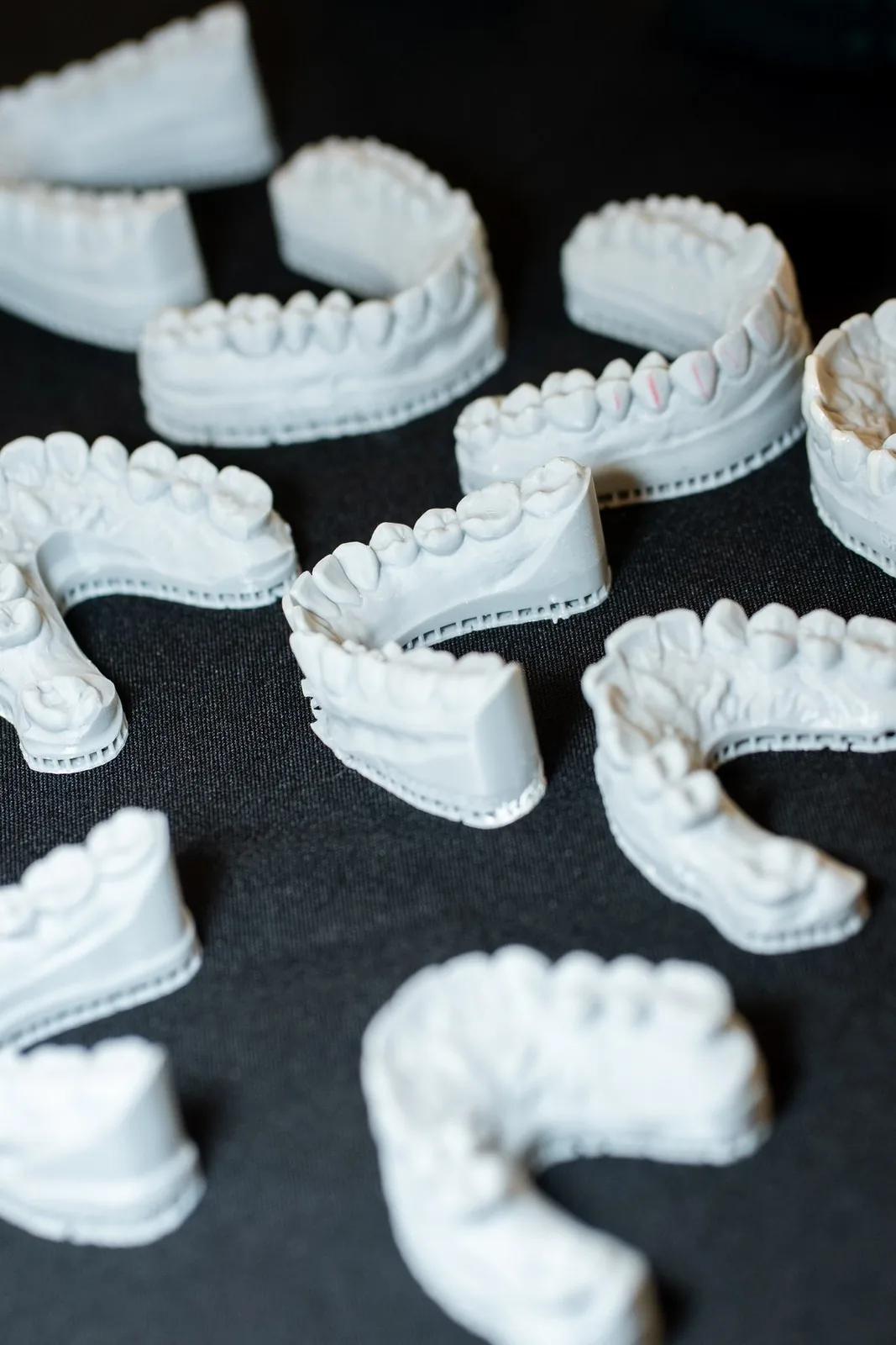 Stone dental models and sectioned arches laid out on black cloth