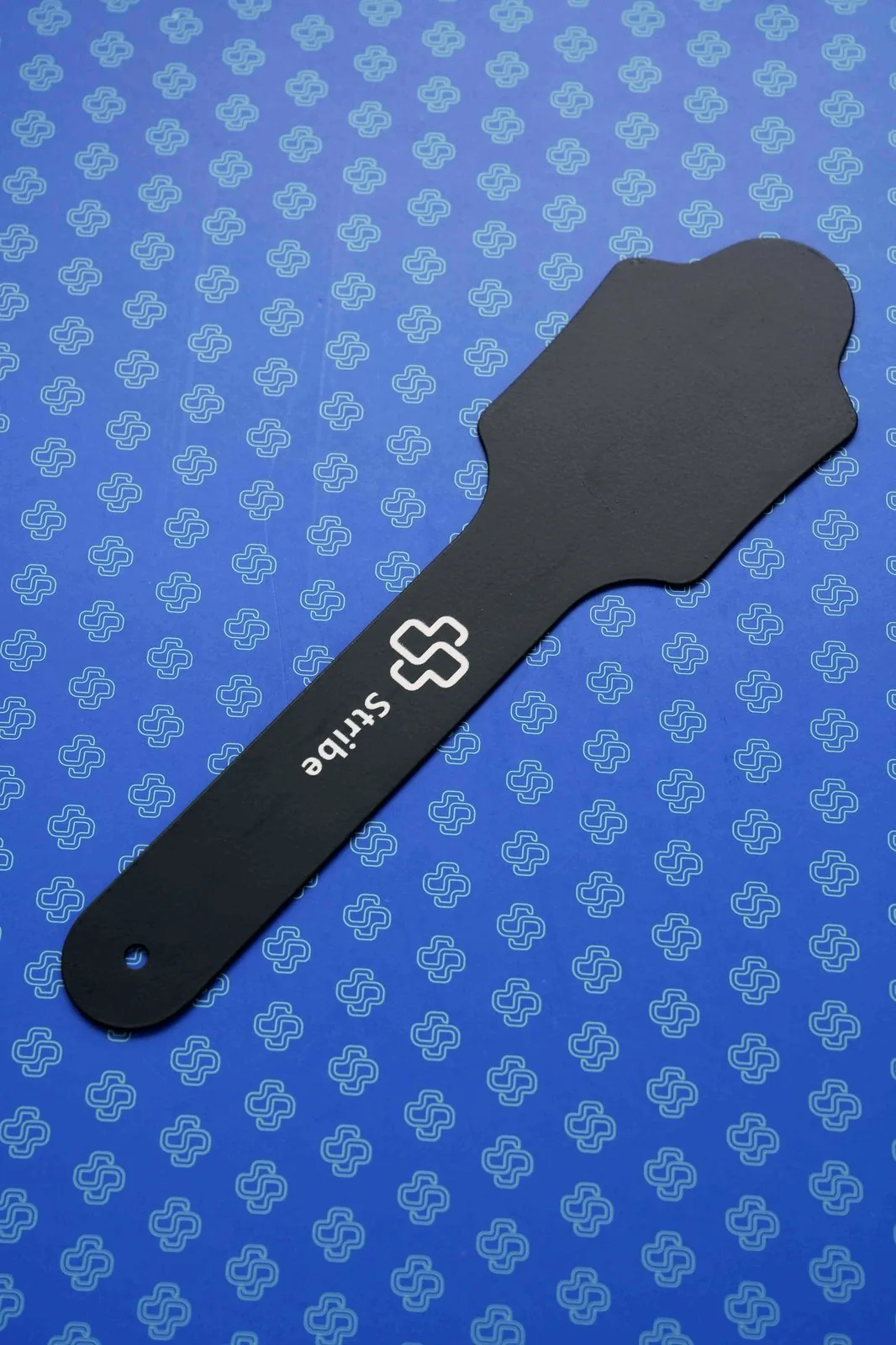 Matte black Stribe contraster paddle for dental photography on a blue patterned backdrop